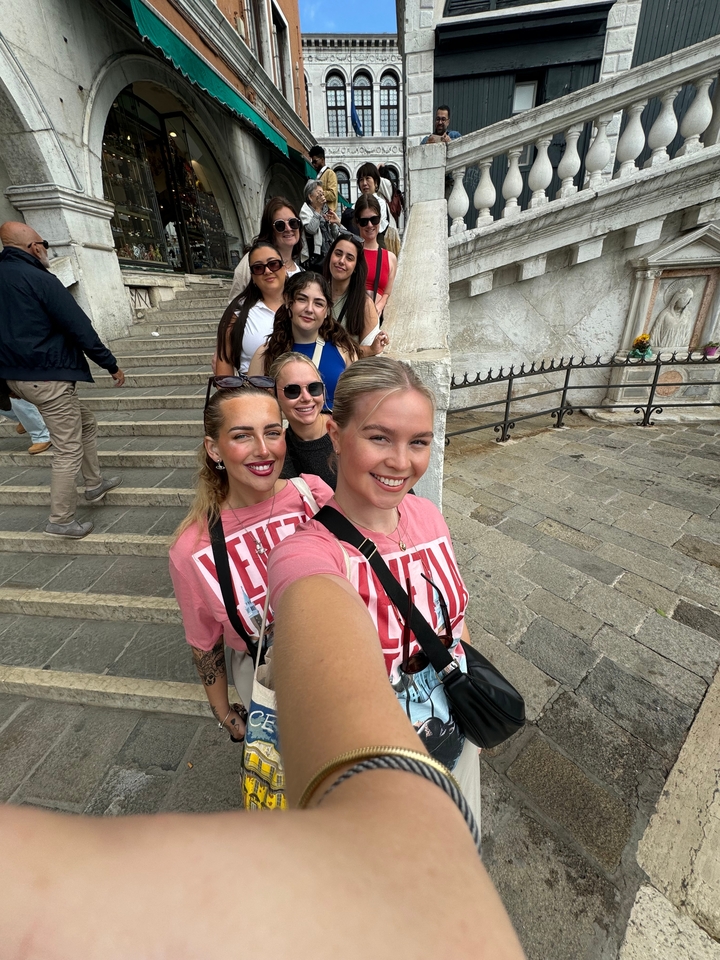 Groupe de femmes prenant un selfie dans des escaliers avec une architecture historique.