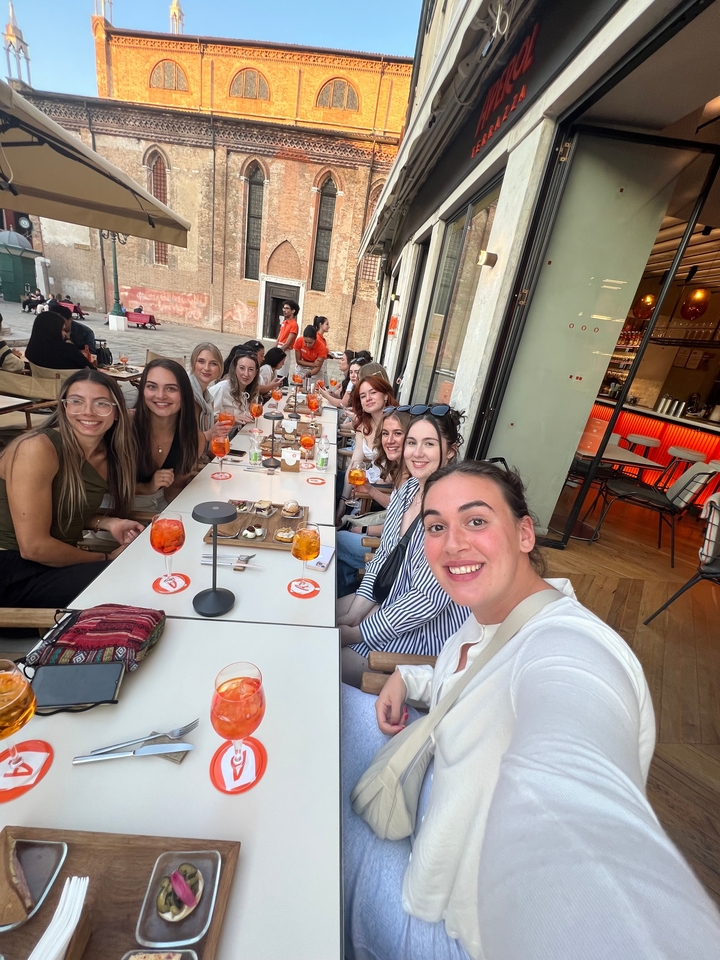 Groupe d'amis dînant dans un restaurant avec des boissons Aperol Spritz visibles.
