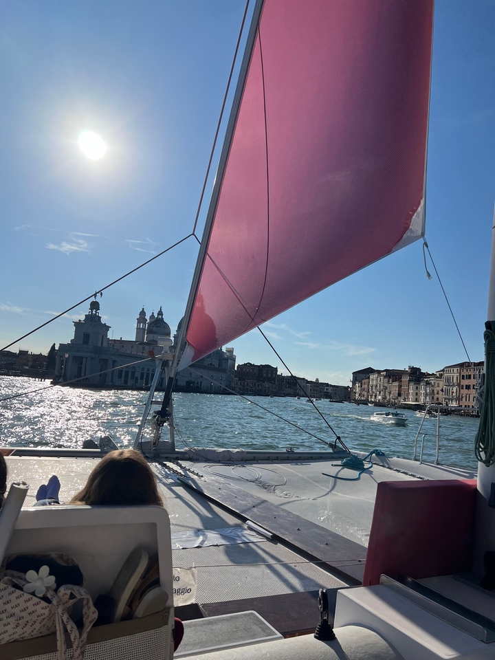 Bateau à voile sur un canal avec des bâtiments historiques visibles.