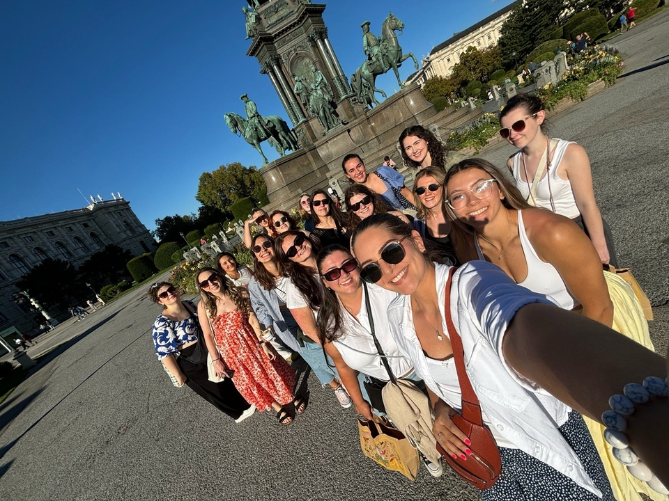 Grand groupe posant près d'un monument historique entouré de statues.