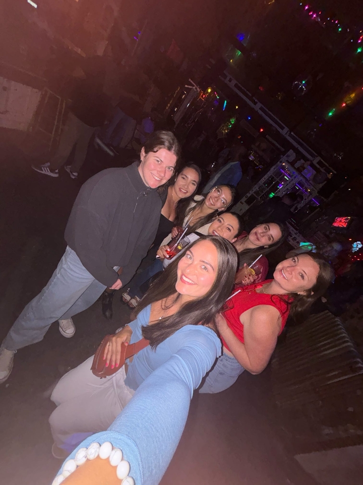 Groupe de personnes lors d'un événement nocturne, tenant des boissons et posant pour une photo.