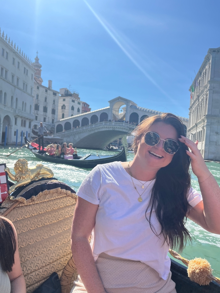 Femme sur une gondole avec le pont du Rialto en arrière-plan.