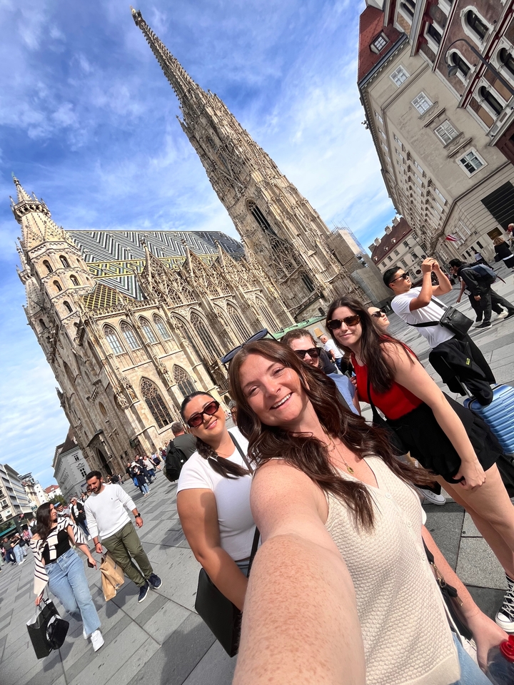 Selfie de groupe devant la façade d'une église historique sur une place de ville.