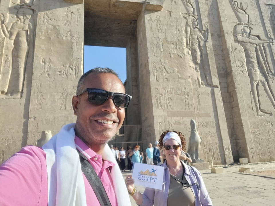 Deux personnes devant des sculptures de temple égyptien antique.