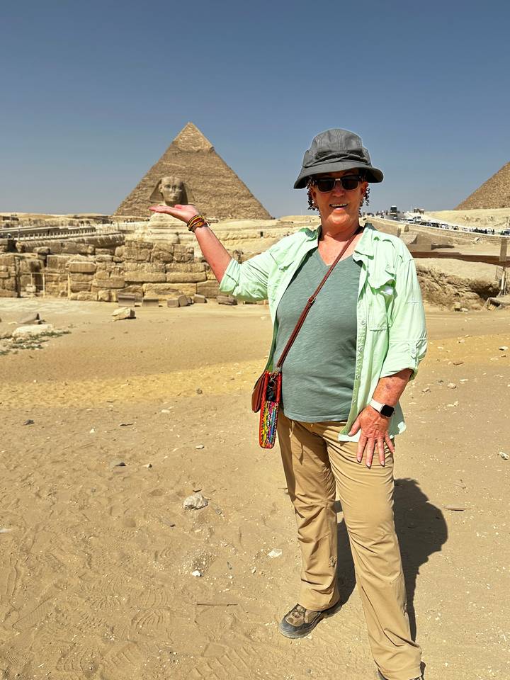 Personne posant avec les pyramides à l'arrière-plan.