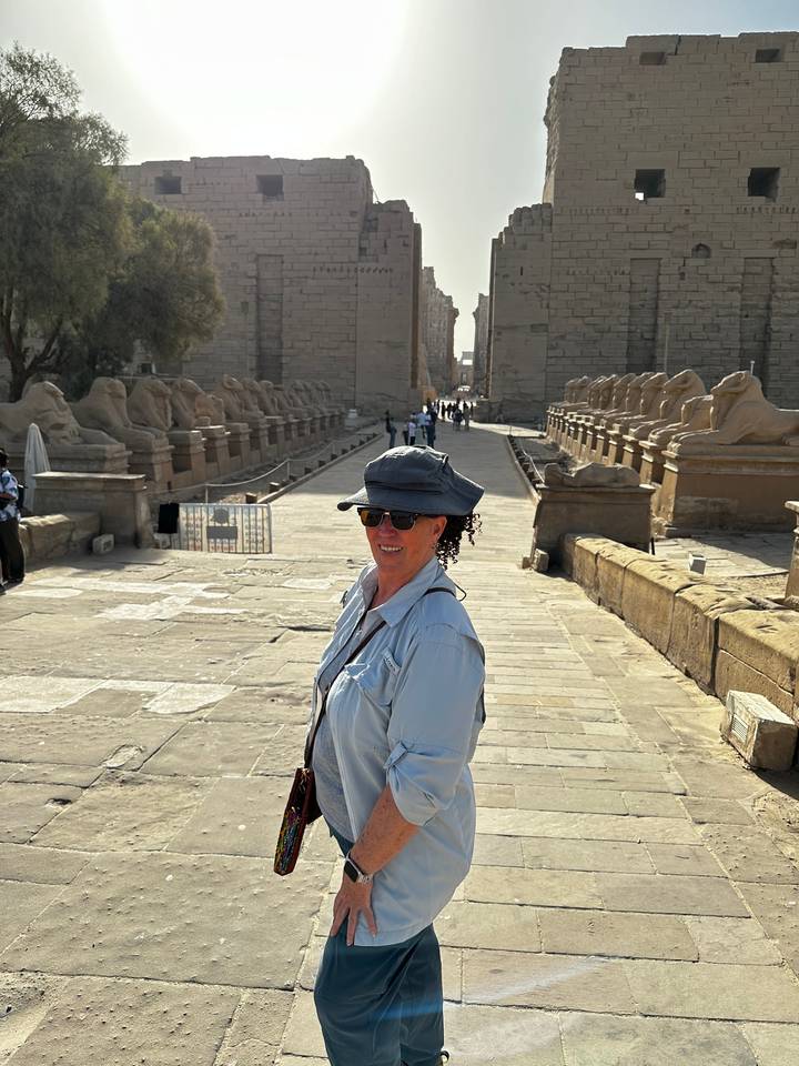 Personne debout devant une rangée de statues à Louxor.
