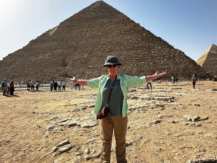Personne les bras ouverts devant une pyramide.