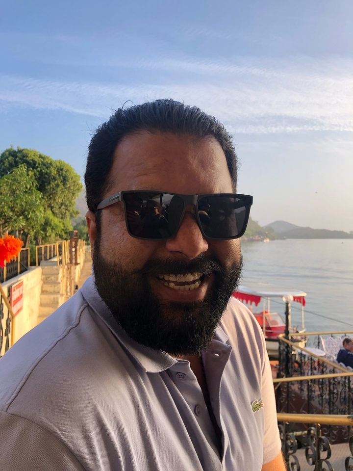 Gros plan d'une personne souriante portant des lunettes de soleil.