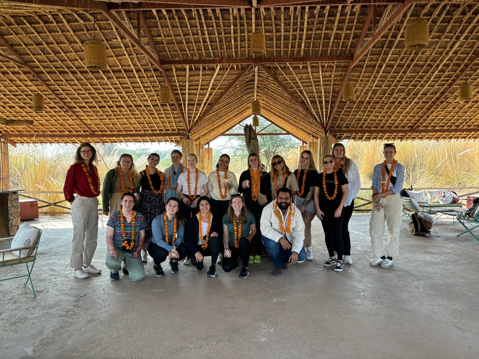 Un groupe de personnes portant des guirlandes dans un bâtiment au toit de chaume.