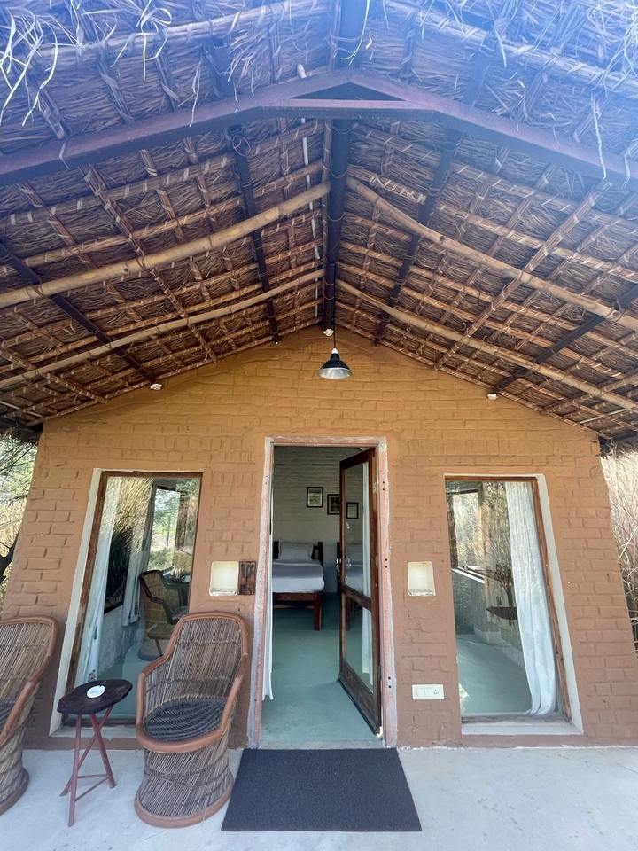 Bâtiment d'hébergement de style adobe avec toit de chaume et portes ouvertes.