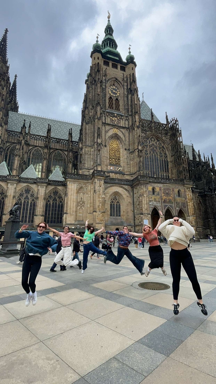 Groupe sautant devant une grande cathédrale à l'architecture ornée