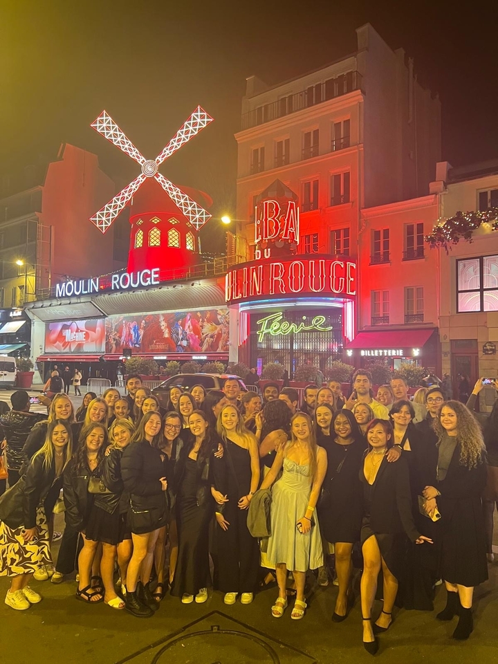 Photo de groupe devant le Moulin Rouge à Paris la nuit