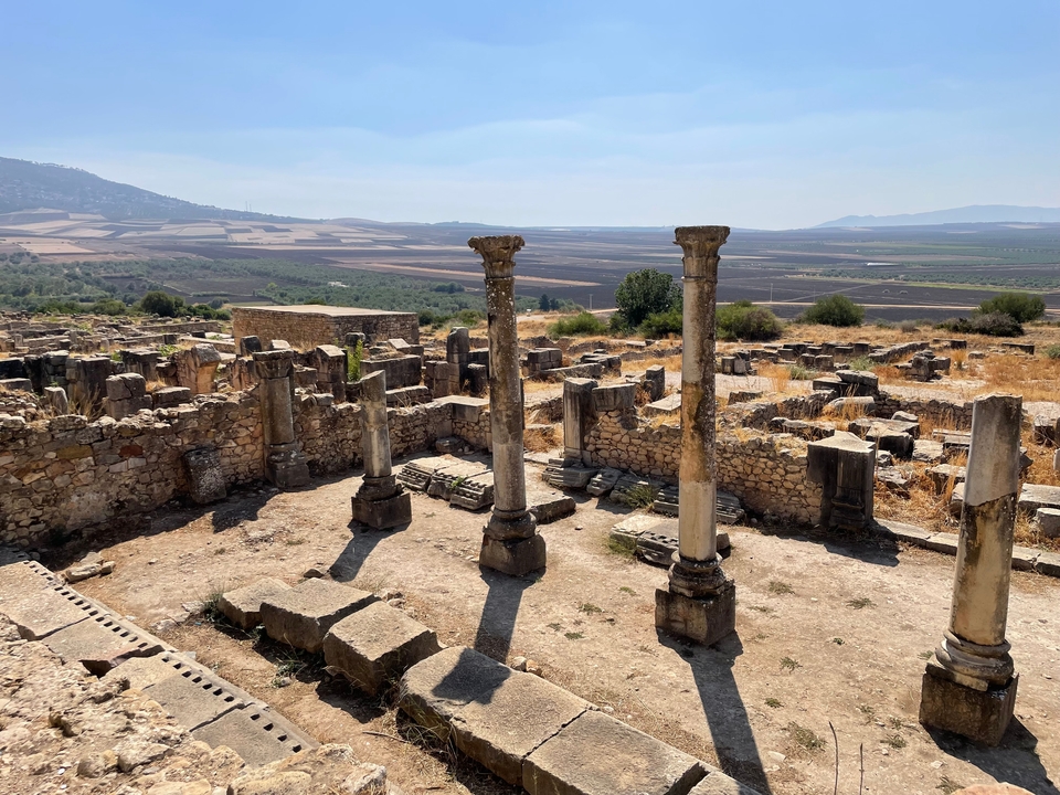 Ruines antiques avec colonnes de pierre dans un paysage rural.