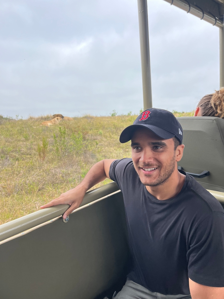Homme assis dans un véhicule de safari avec un lion visible à l'extérieur.