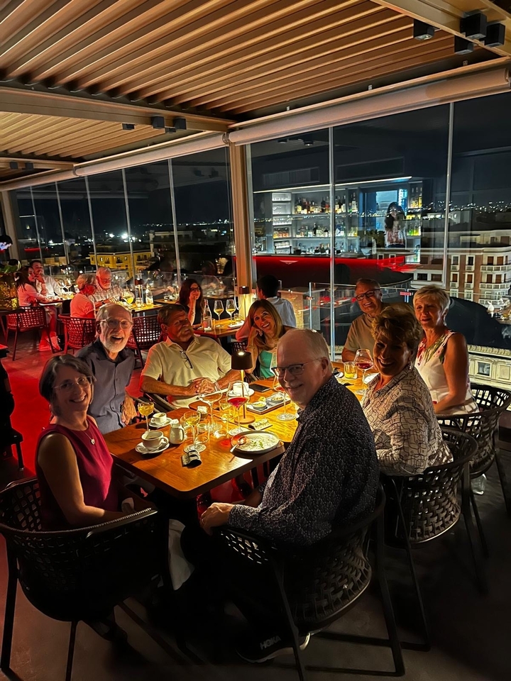 Dîner de groupe dans un restaurant aux murs de verre avec vue sur la ville la nuit.