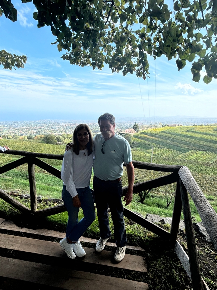 Deux personnes sur un balcon donnant sur des vignobles.