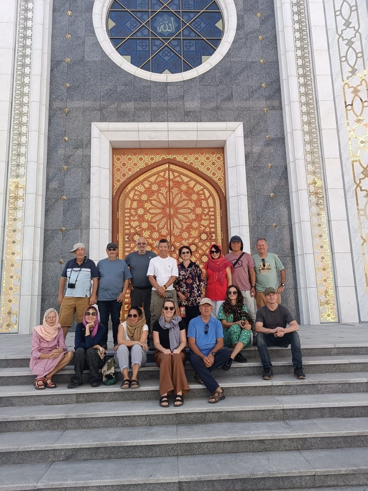 Grupo de turistas posando frente a la entrada de un edificio ornamentado.