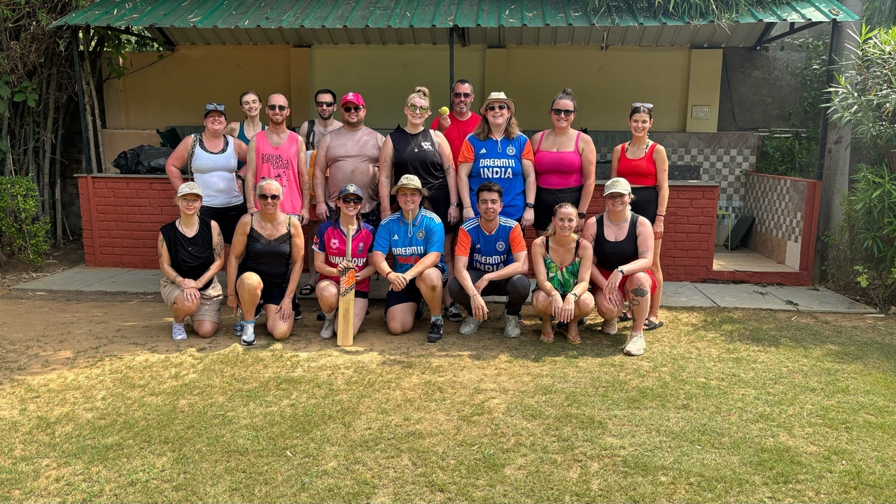 Un groupe de personnes posant dans un espace herbeux ouvert avec un petit bâtiment derrière.