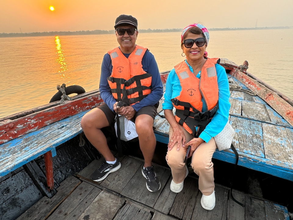 Deux personnes portant des gilets de sauvetage assises dans un bateau au coucher du soleil.