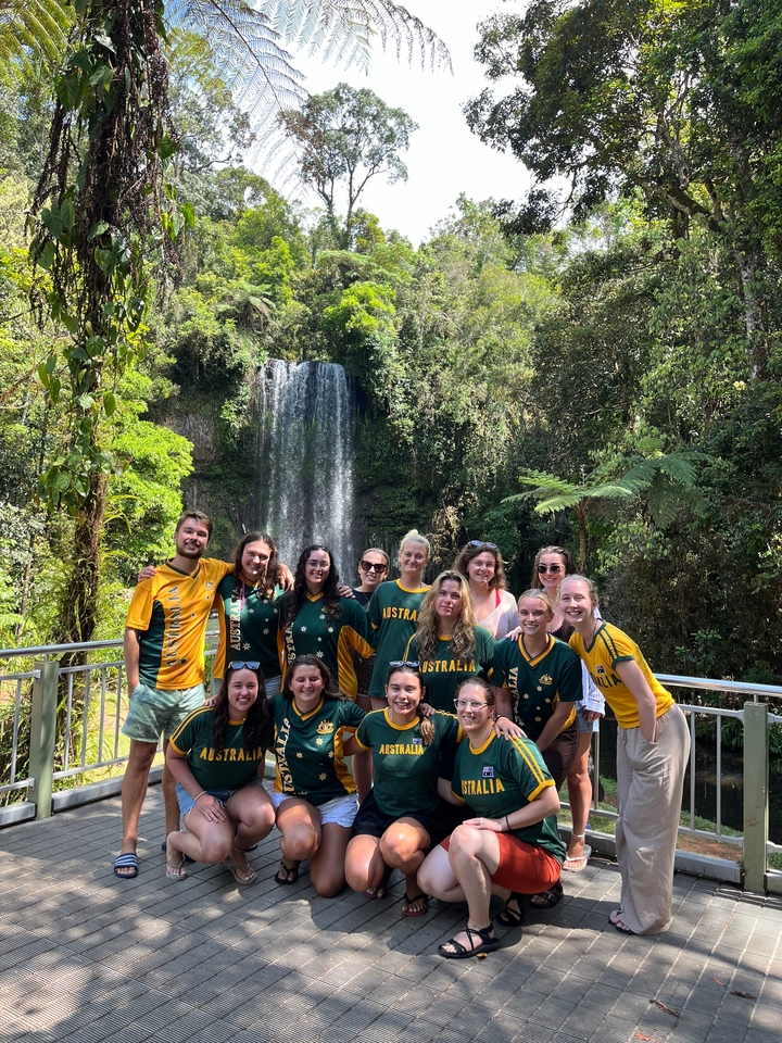 Groupe de personnes posant devant une cascade dans une zone forestière.