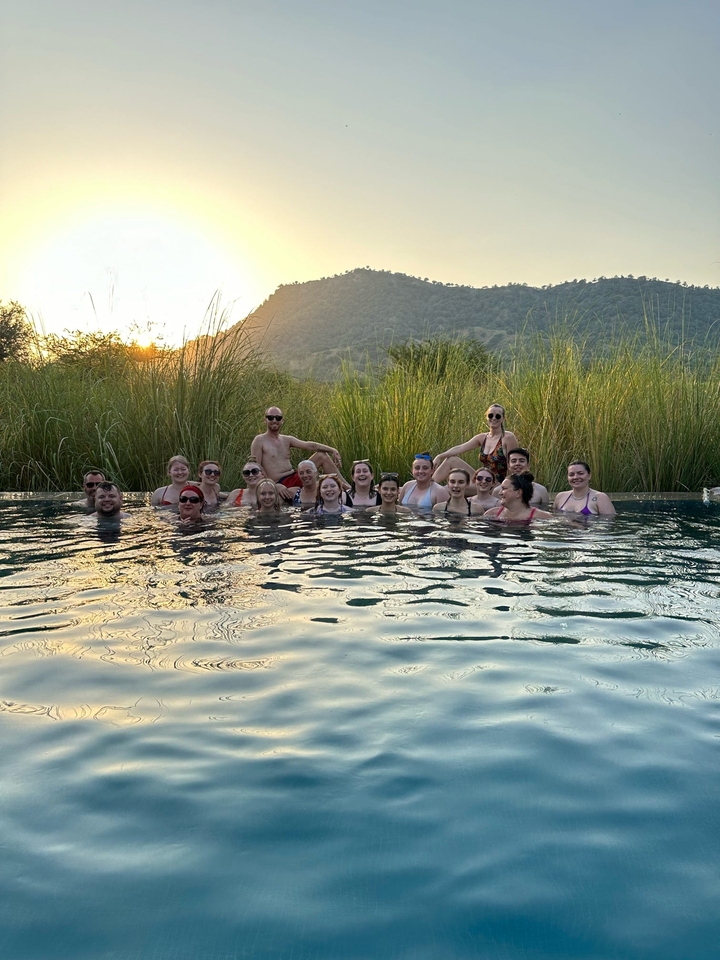 Groupe de personnes dans une piscine avec un paysage naturel en arrière-plan.