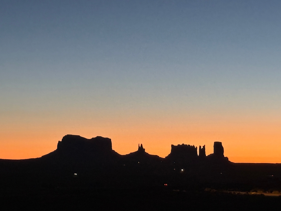 Silhouette de formations rocheuses contre un ciel de coucher de soleil coloré.