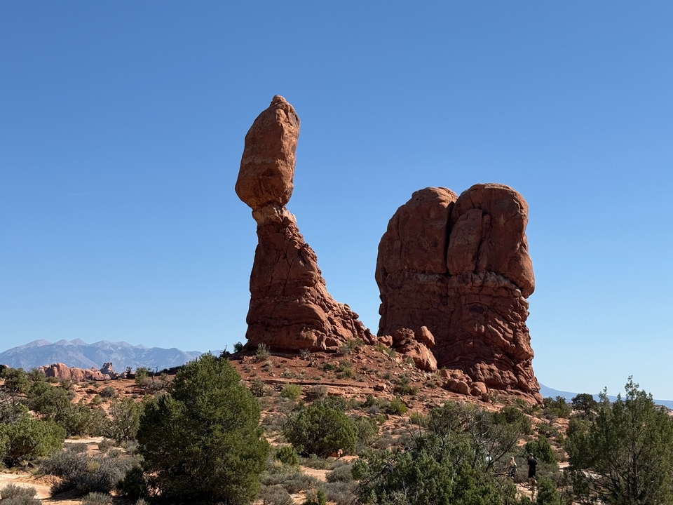 Formation rocheuse ressemblant à une sculpture en équilibre sur fond de ciel bleu.