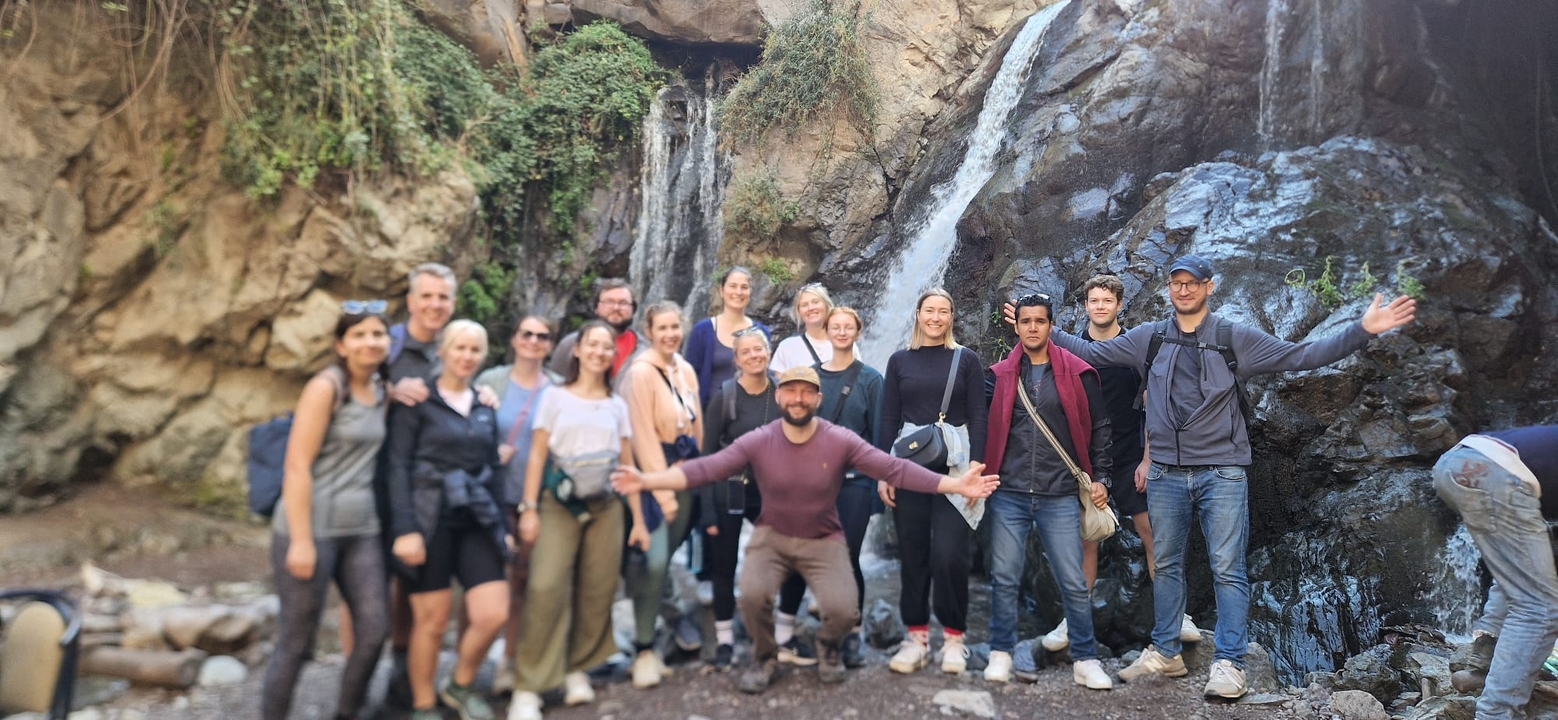 Gruppe von Menschen an einem Wasserfall in einer Waldumgebung.