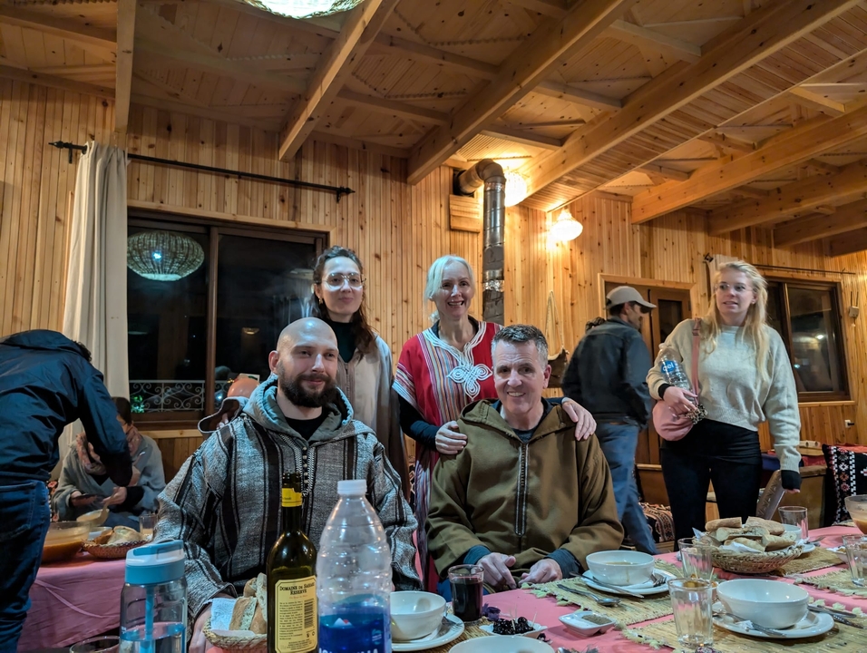Gruppe von Menschen versammelt in einem Raum mit Holzeinrichtung mit Essen und Getränken.