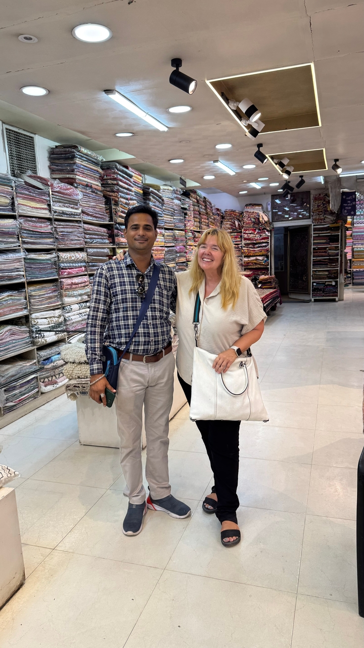 Deux personnes posant dans un magasin de tissus avec divers textiles.