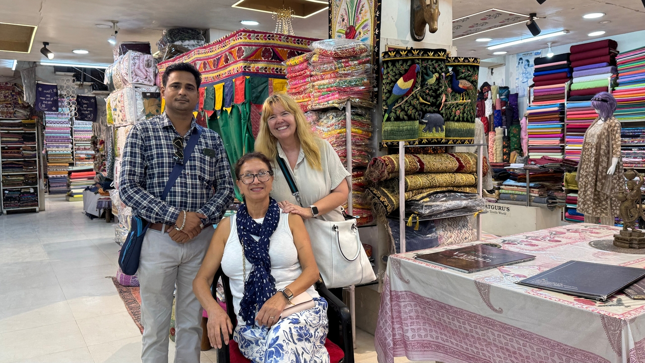 Trois personnes posant dans un magasin de tissus colorés.
