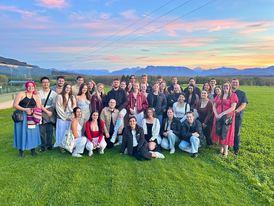 Groupe de personnes posant devant un paysage montagneux pittoresque au coucher du soleil.