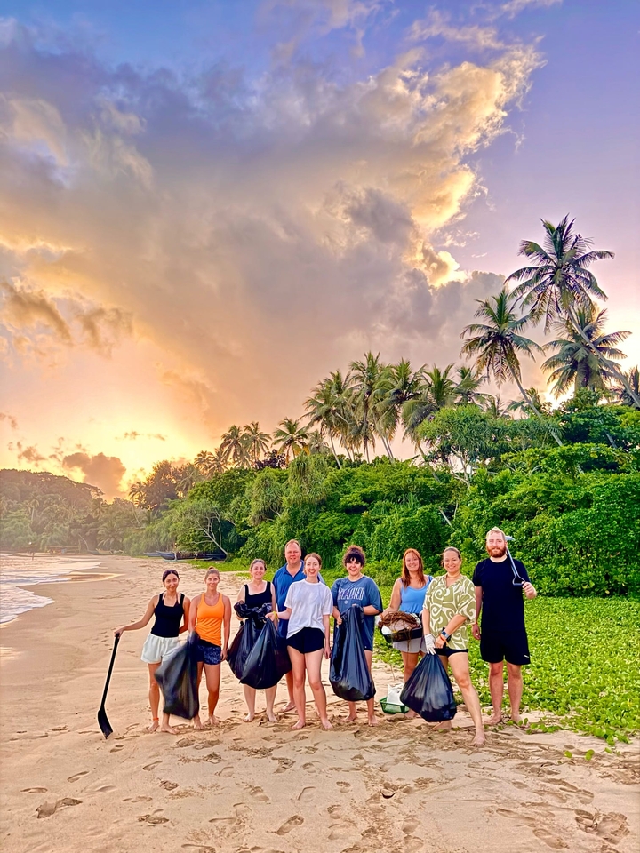 Groupe de personnes sur une plage avec un coucher de soleil en arrière-plan.