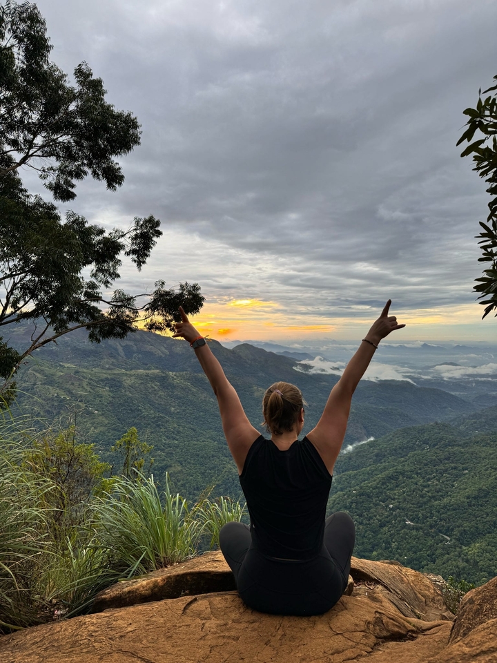 Personne célébrant au sommet d'une montagne au lever du soleil.