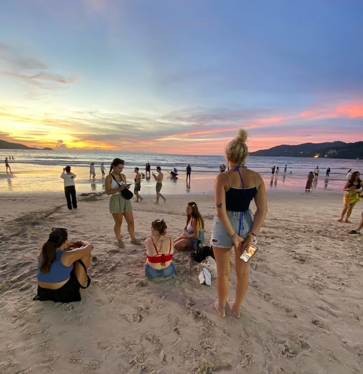 Des gens se sont rassemblés sur une plage au coucher du soleil.