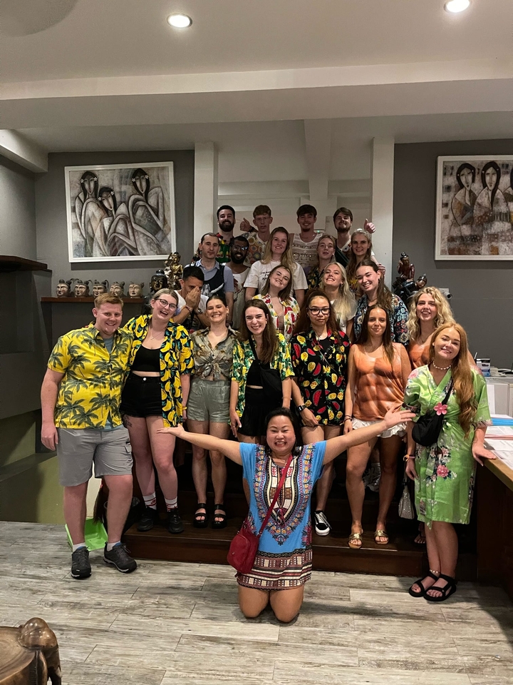 Grand groupe de personnes posant en tenues colorées à l'intérieur.