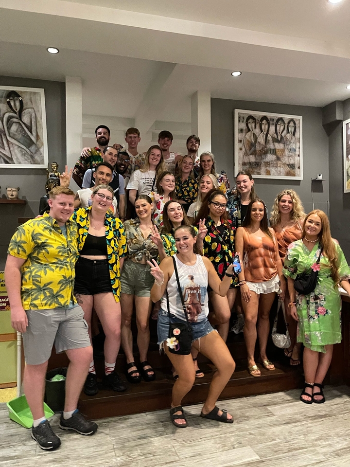 Grand groupe de personnes posant en tenues colorées à l'intérieur.