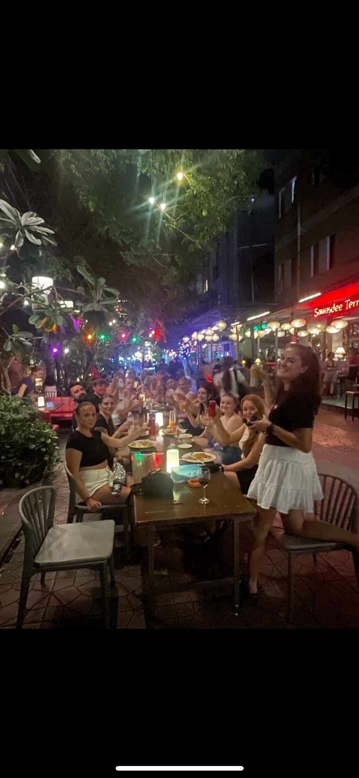 Repas de groupe en plein air avec des éclairages vibrants et des décorations.