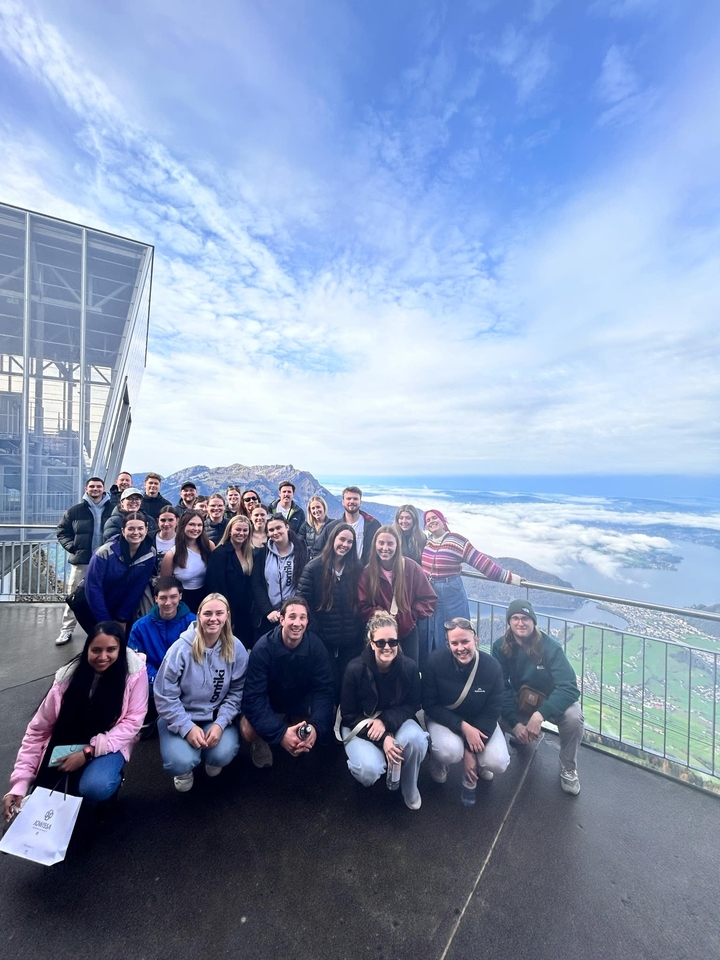 Groupe posant à un point de vue élevé avec montagnes et nuages.