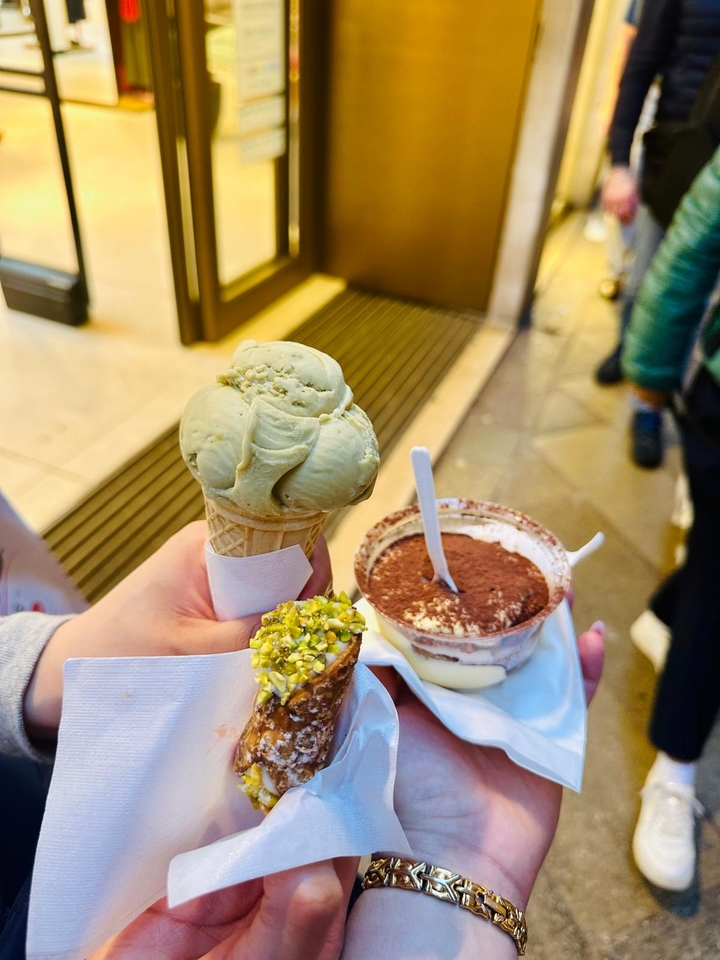 Main tenant un cornet de glace et une coupe de dessert dans la rue.