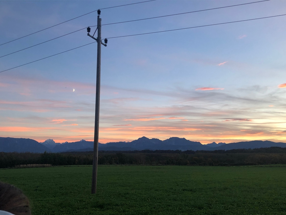 Coucher de soleil avec silhouette de montagne et nuages dans le ciel.