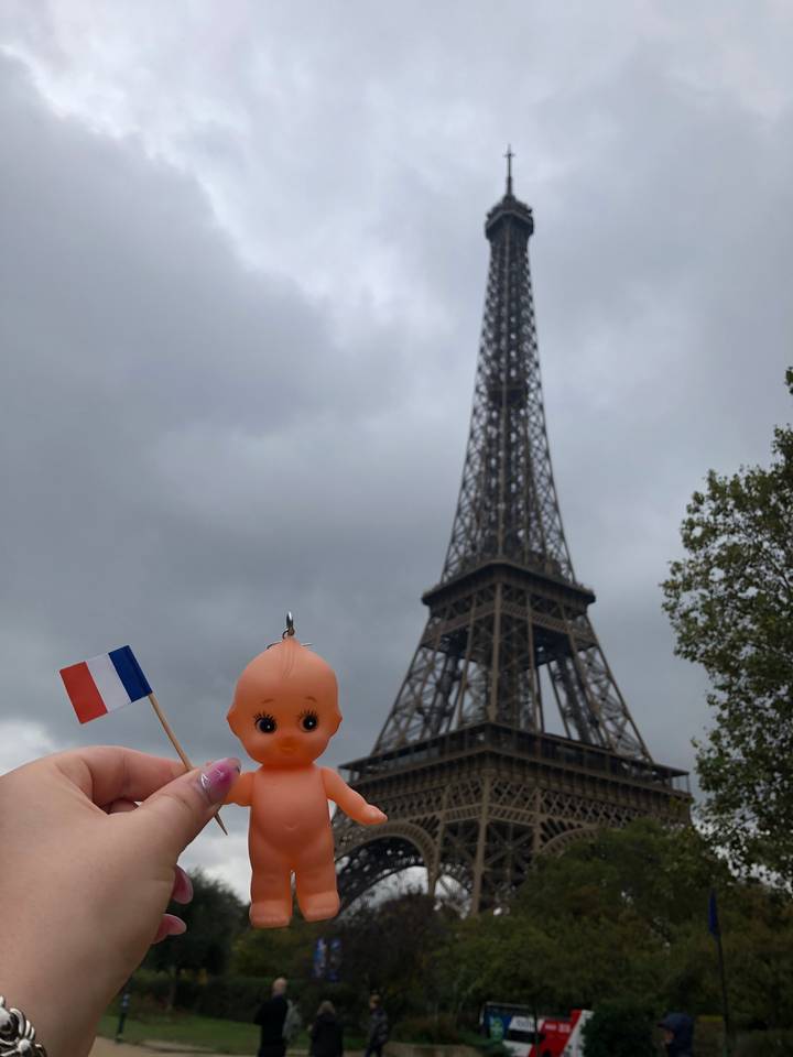 Tour Eiffel avec un petit jouet tenant un drapeau français au premier plan.