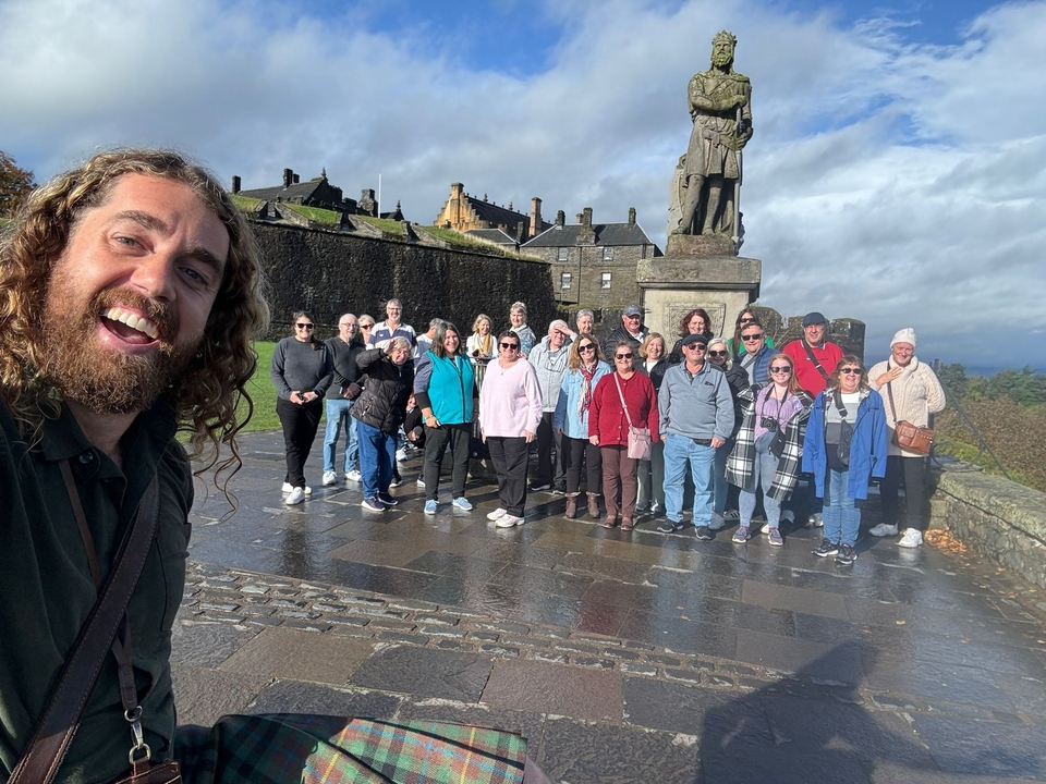 Grand groupe posant devant une statue et un bâtiment historique.