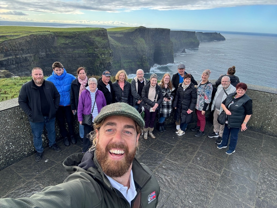 Groupe de personnes posant avec une vue sur l'océan depuis une falaise.