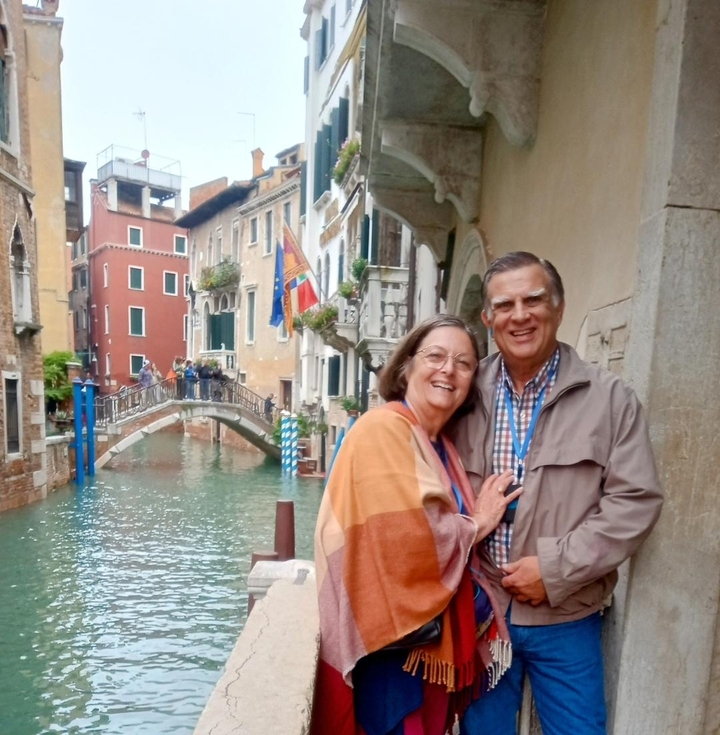 Couple posant près d'un canal dans une ville aux bâtiments colorés.