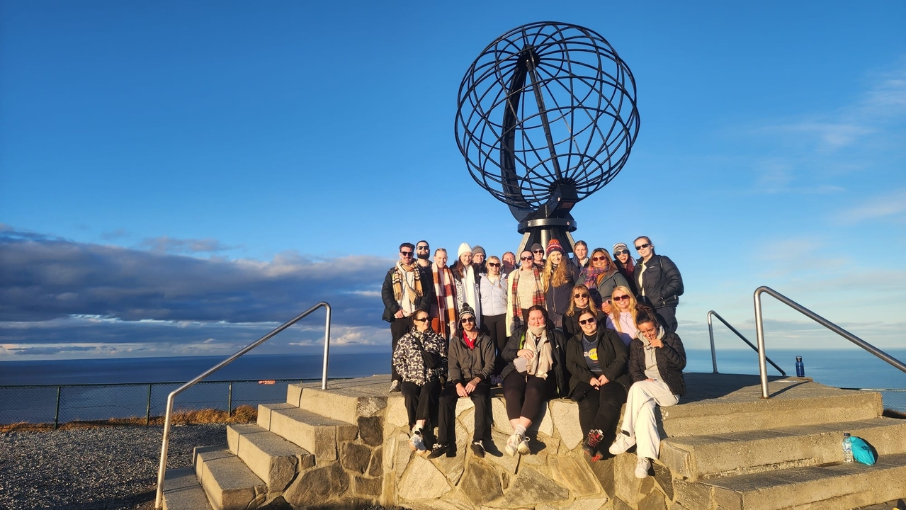 Photo de groupe devant un globe monumental au bord de la mer.