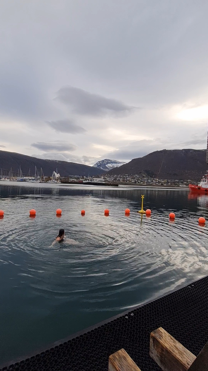 Personne nageant dans un port avec des montagnes.