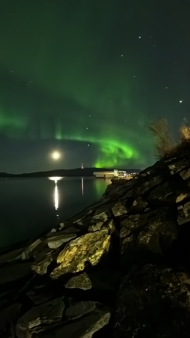 Aurores boréales au-dessus de l'eau avec reflets.