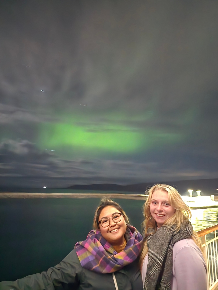 Aurores boréales avec deux personnes faiblement visibles.