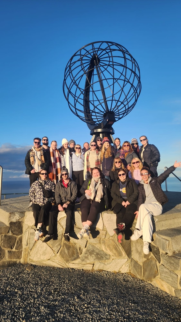 Photo de groupe devant le monument avec un ciel ensoleillé.